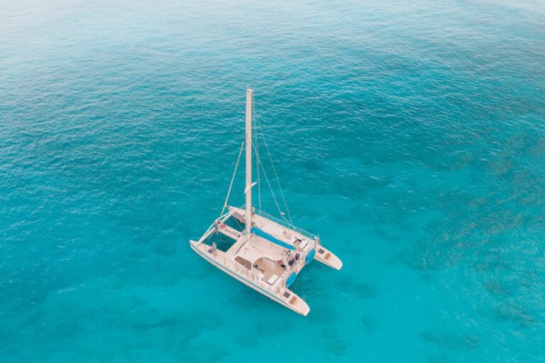 Stunning aerial view of a catamaran sailing in crystal clear turquoise waters.